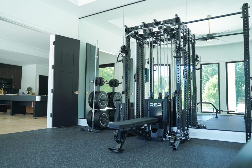 Custom home gym design with a power rack, large mirrors, and windows